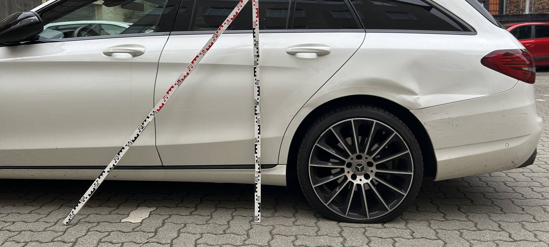 Oranger Fremdlack auf der dunklen Flanke eines Hyundai ix35, Beschädigung über beide Türen